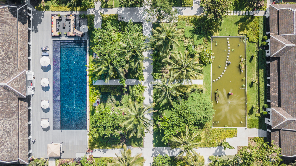 Aerial view of the Sofitel Luang Prabang Laos, including a view of their beautiful lush botanical gardens and sparling amethyst-tonedpool.