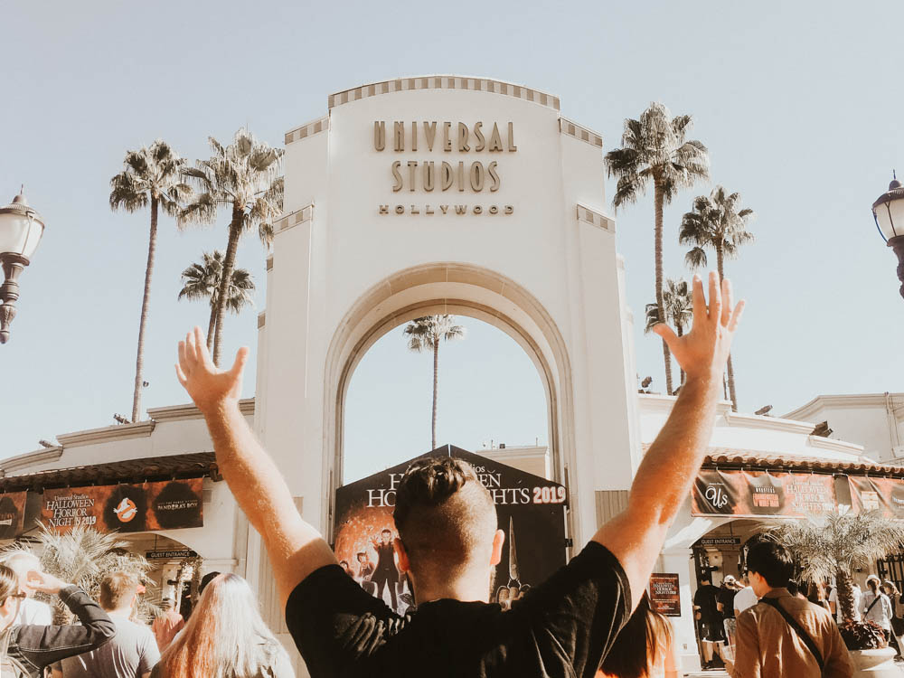 Ben standing at the entrance for Universal Studios Hollywood with his arms in the air.
